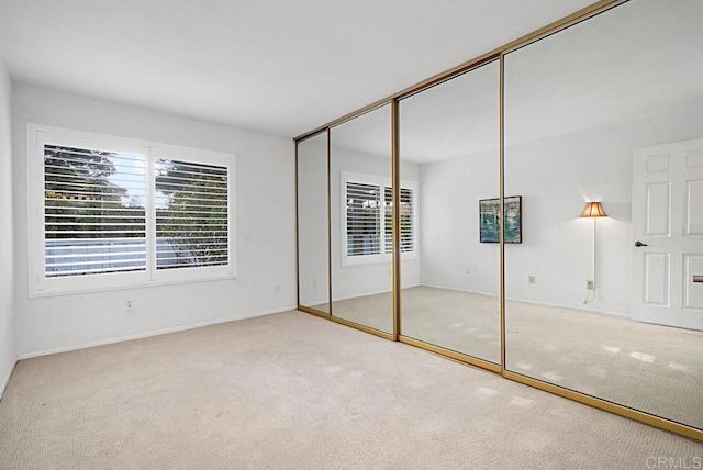 unfurnished bedroom featuring light carpet and a closet