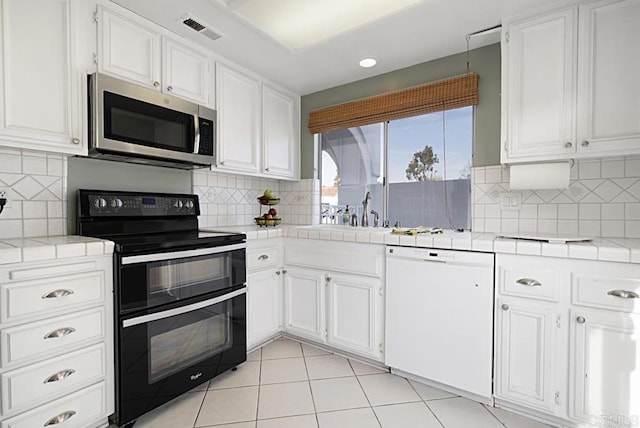 kitchen with sink, white dishwasher, tile counters, white cabinets, and range with two ovens