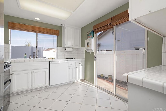 kitchen with white cabinetry, tile countertops, dishwasher, and range