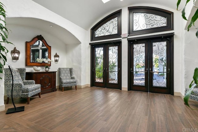 foyer entrance featuring vaulted ceiling, hardwood / wood-style floors, and french doors