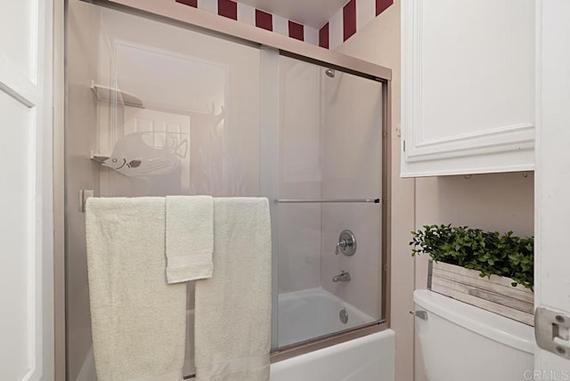 bathroom featuring toilet and bath / shower combo with glass door