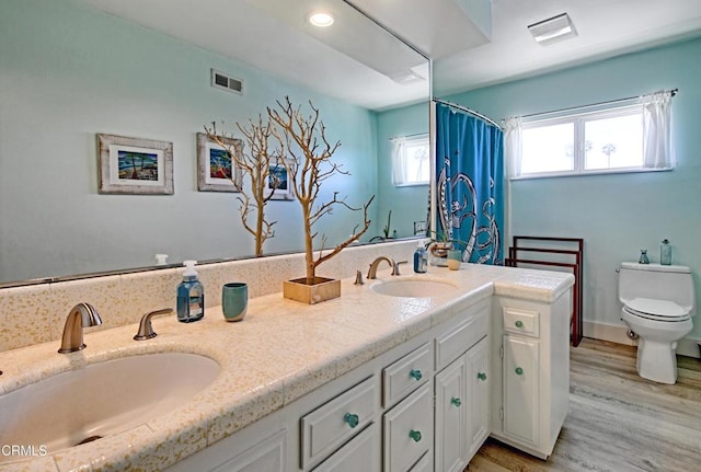 bathroom featuring vanity, wood-type flooring, toilet, and walk in shower