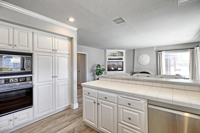 kitchen with white cabinetry, tile counters, light wood-type flooring, and black appliances