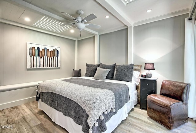 bedroom with ceiling fan, light wood-type flooring, and beam ceiling