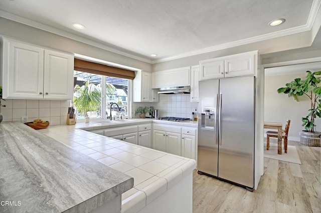 kitchen featuring white cabinetry, sink, tile counters, light hardwood / wood-style floors, and stainless steel appliances