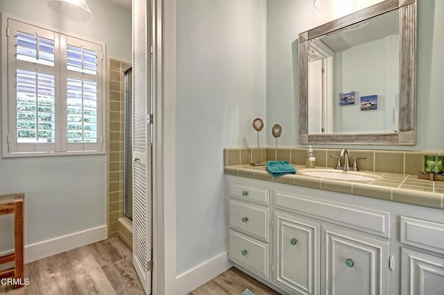 bathroom with vanity, baseboards, walk in shower, and wood finished floors