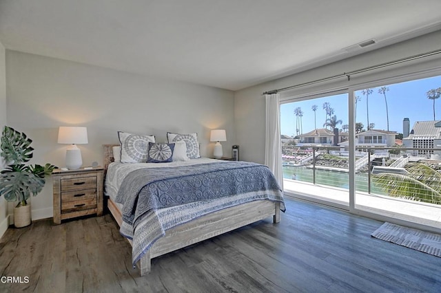 bedroom featuring access to exterior, wood finished floors, baseboards, and visible vents