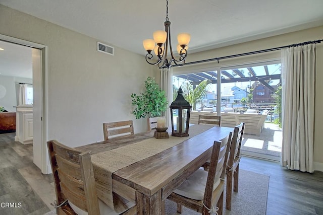 dining space featuring a notable chandelier, visible vents, and wood finished floors