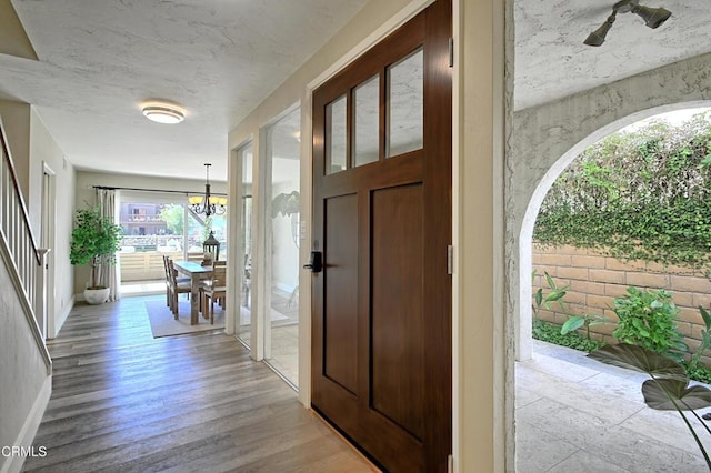 foyer with light wood-type flooring, a notable chandelier, and baseboards
