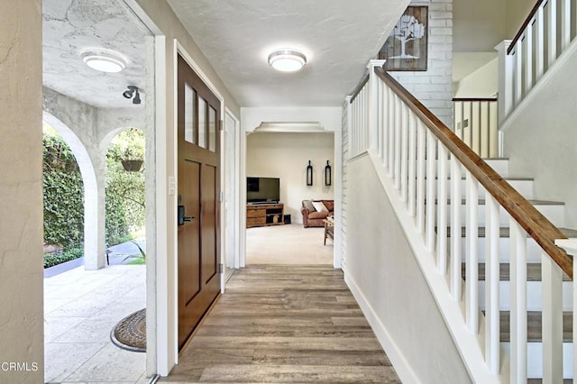 entrance foyer with wood finished floors, baseboards, and stairway