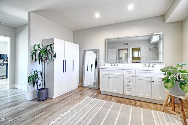 bathroom with double vanity, recessed lighting, visible vents, a sink, and wood finished floors
