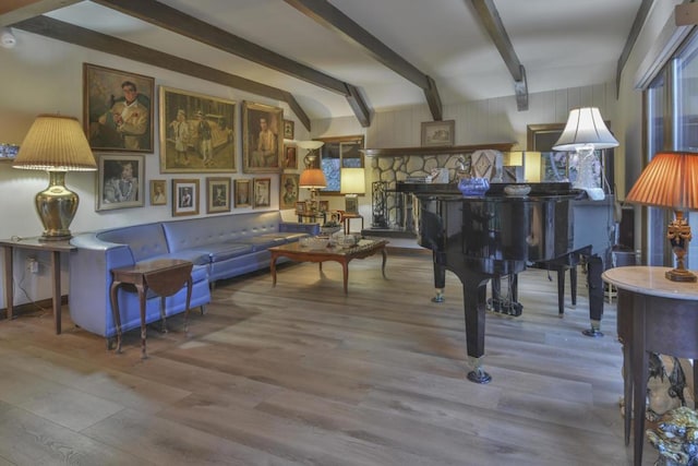 miscellaneous room with wood-type flooring, a stone fireplace, and vaulted ceiling with beams