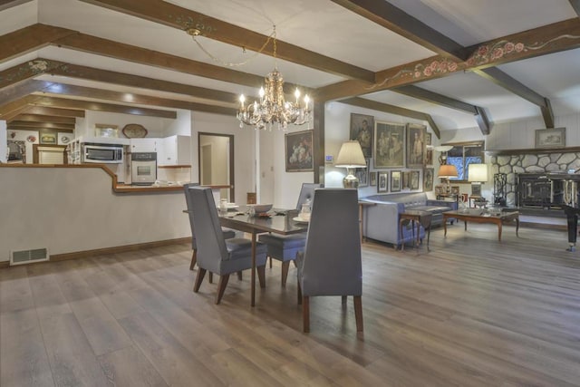 dining room with a notable chandelier, wood-type flooring, and beamed ceiling