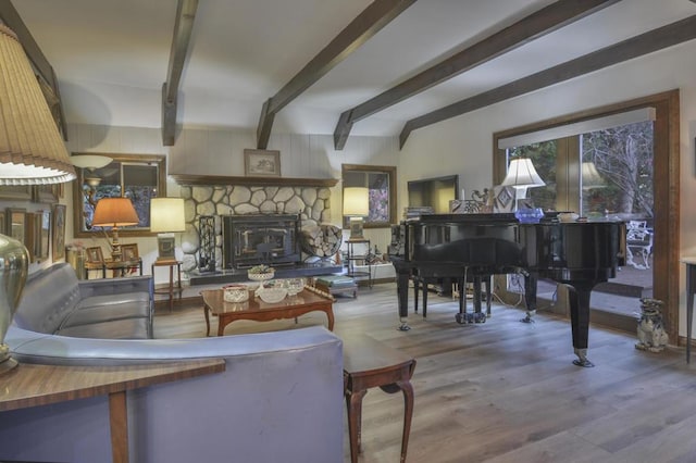 living room featuring beam ceiling, hardwood / wood-style floors, and a stone fireplace