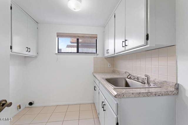 clothes washing area with cabinets, sink, and light tile patterned floors