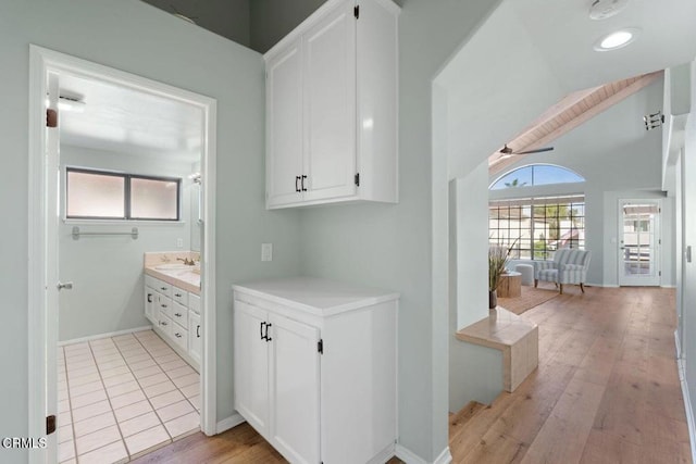 hall featuring lofted ceiling, sink, and light hardwood / wood-style floors