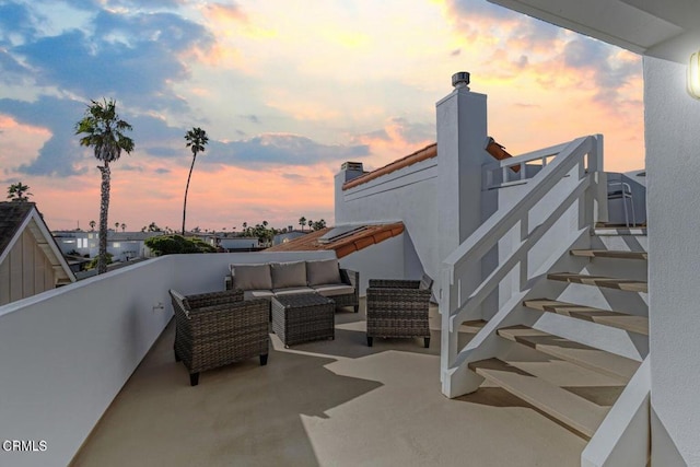 patio terrace at dusk featuring outdoor lounge area and a balcony