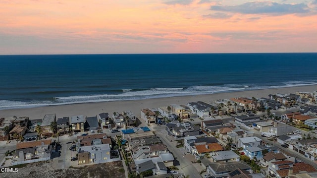 aerial view at dusk with a water view and a view of the beach