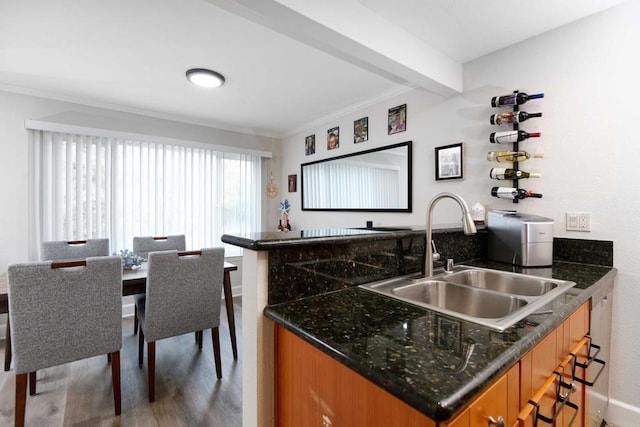 kitchen featuring sink, a breakfast bar area, hardwood / wood-style floors, beam ceiling, and ornamental molding