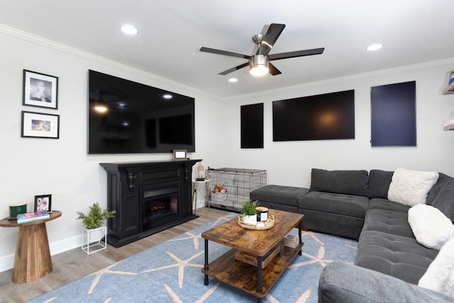 living room with wood-type flooring, ornamental molding, and ceiling fan