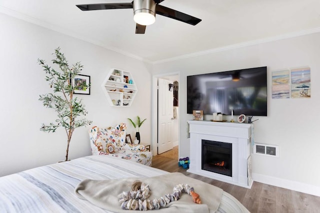 bedroom with wood-type flooring, ceiling fan, and crown molding