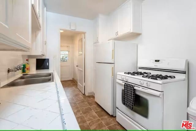 kitchen with sink, white gas stove, and white cabinets