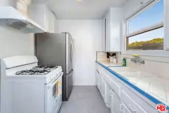 kitchen featuring sink, white gas range oven, and white cabinets