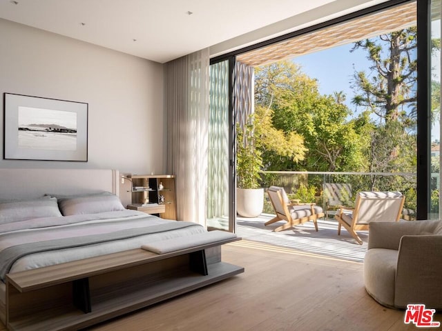 bedroom with a wall of windows, wood-type flooring, access to exterior, and multiple windows