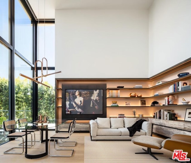 living room with hardwood / wood-style flooring, a towering ceiling, and a wall of windows