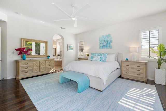 bedroom featuring multiple windows, ensuite bathroom, dark wood-type flooring, and ceiling fan