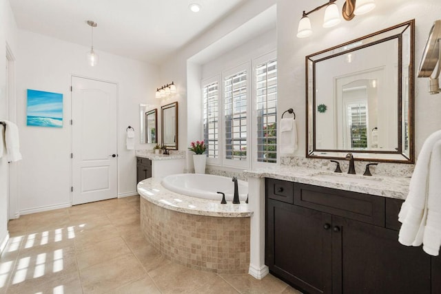 bathroom featuring a relaxing tiled tub, vanity, and tile patterned flooring