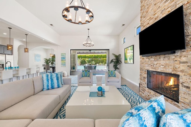 living room featuring a stone fireplace and a chandelier