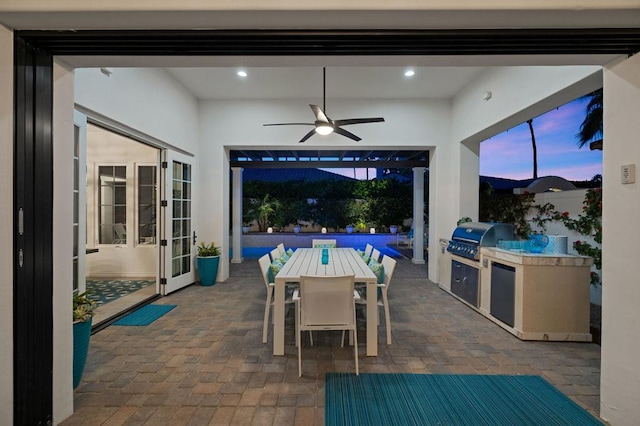 patio terrace at dusk featuring area for grilling and ceiling fan