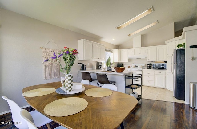 dining space featuring high vaulted ceiling and light wood-type flooring