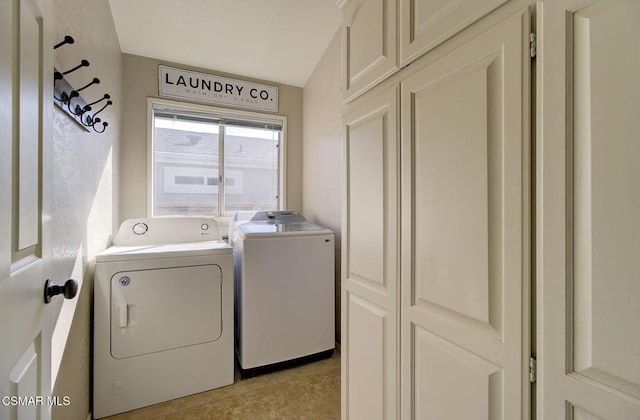 laundry room featuring washer and clothes dryer and cabinets