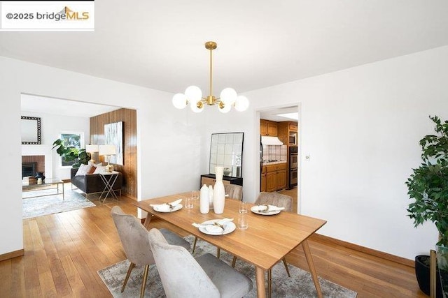 dining room with a fireplace, hardwood / wood-style floors, and a notable chandelier