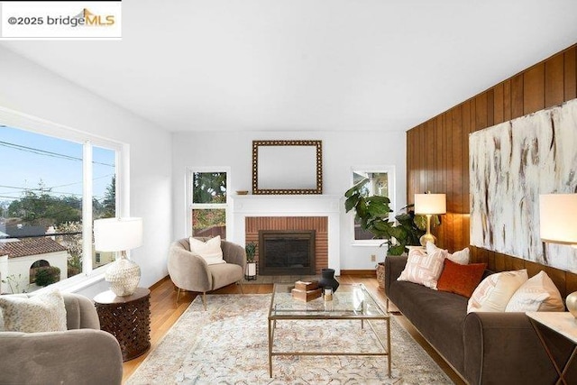 living room with wood-type flooring, a fireplace, and wood walls