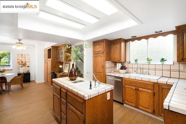 kitchen with dishwasher, a center island, tile counters, and light wood-type flooring