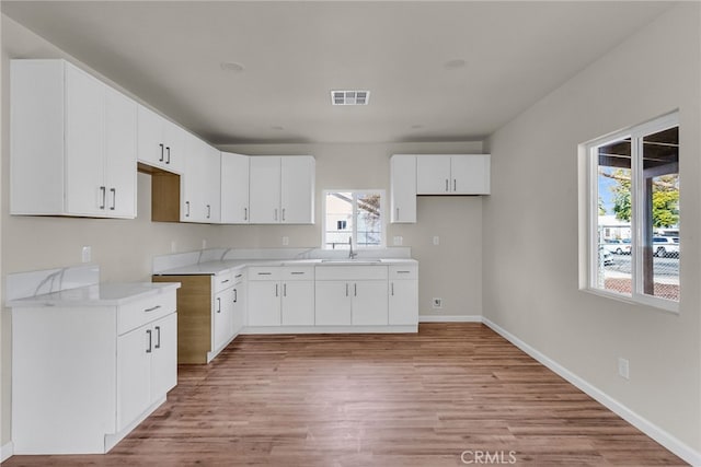 kitchen featuring sink, light hardwood / wood-style flooring, and white cabinets