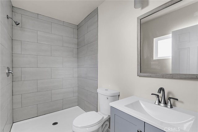 bathroom with tiled shower, vanity, and toilet