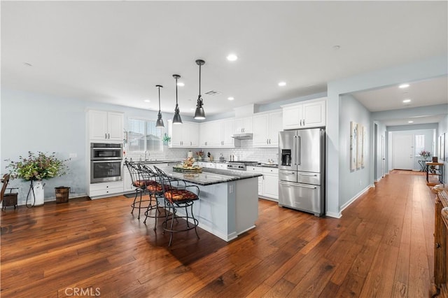 kitchen featuring appliances with stainless steel finishes, a kitchen bar, a kitchen island, and white cabinets