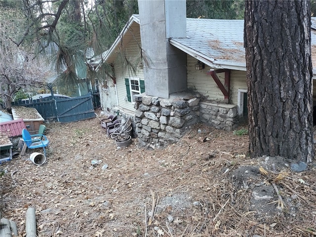 view of property exterior with a chimney and fence