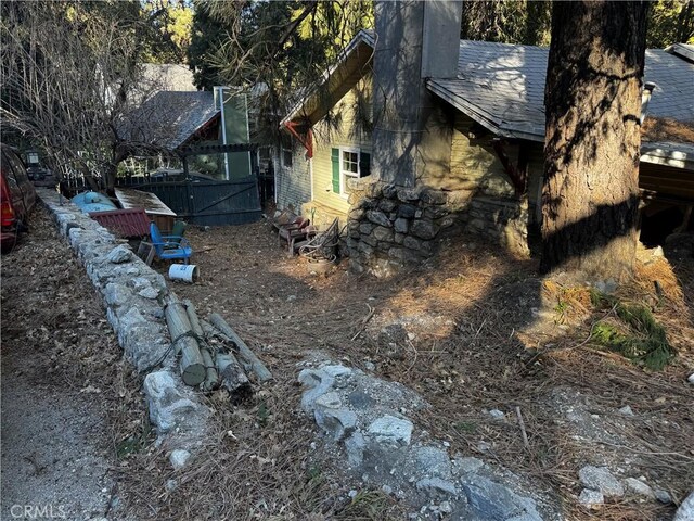 view of side of property featuring a shingled roof and fence