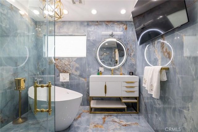 bathroom with vanity, tile walls, a bathing tub, and an inviting chandelier