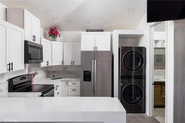 kitchen with white cabinetry, stacked washer and dryer, sink, and appliances with stainless steel finishes