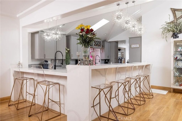 kitchen with a kitchen breakfast bar, gray cabinets, and kitchen peninsula