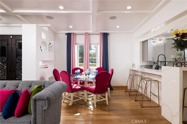 dining area featuring beamed ceiling, wood-type flooring, coffered ceiling, and sink