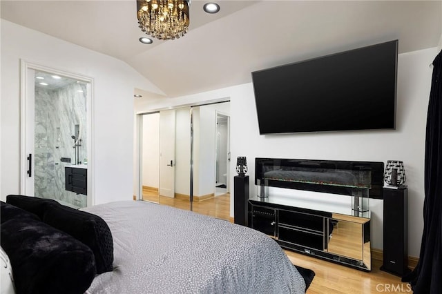 bedroom with an inviting chandelier, ensuite bath, vaulted ceiling, light hardwood / wood-style flooring, and a closet