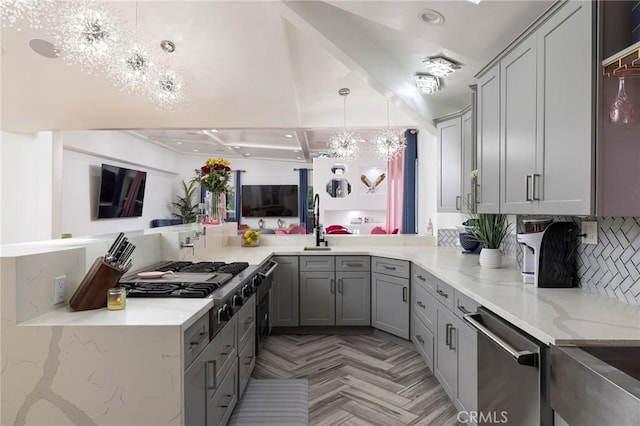 kitchen featuring pendant lighting, gray cabinets, a notable chandelier, light stone countertops, and light parquet flooring