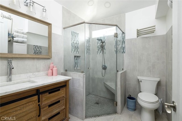 bathroom featuring tile walls, tile patterned flooring, vanity, an enclosed shower, and toilet